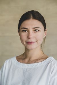Portrait of a Progressive Learning Academy tutor, smiling warmly in a professional headshot with a neutral background.